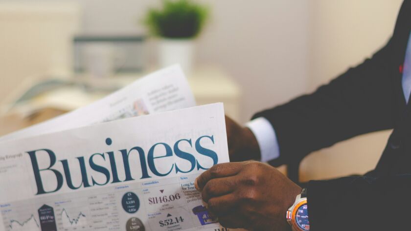 A business energy broker reading the financial section of a newspaper, focusing on energy markets and industry trends.