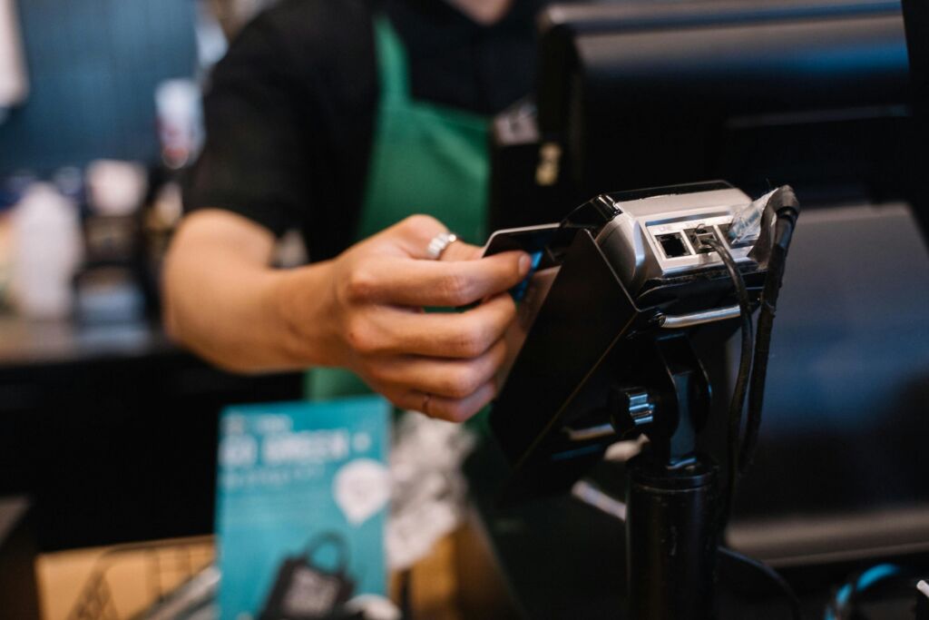 Employee swiping a credit card on a business card machine, with blurred background.