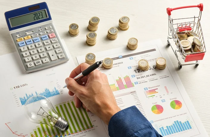 A calculator, pen, gas bill, and coins on a small trolley, illustrating savings with a business gas broker.