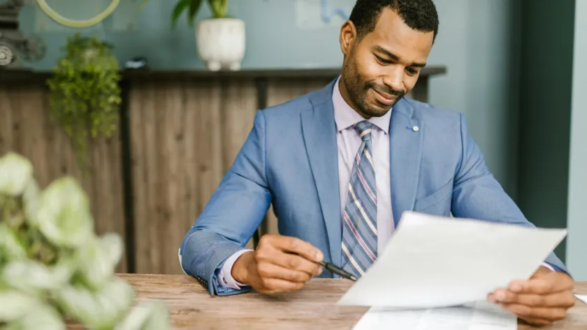 A professional energy broker in the UK wearing a blue suit jacket, holding a white paper and a ballpoint pen, symbolizing expertise and business negotiations.