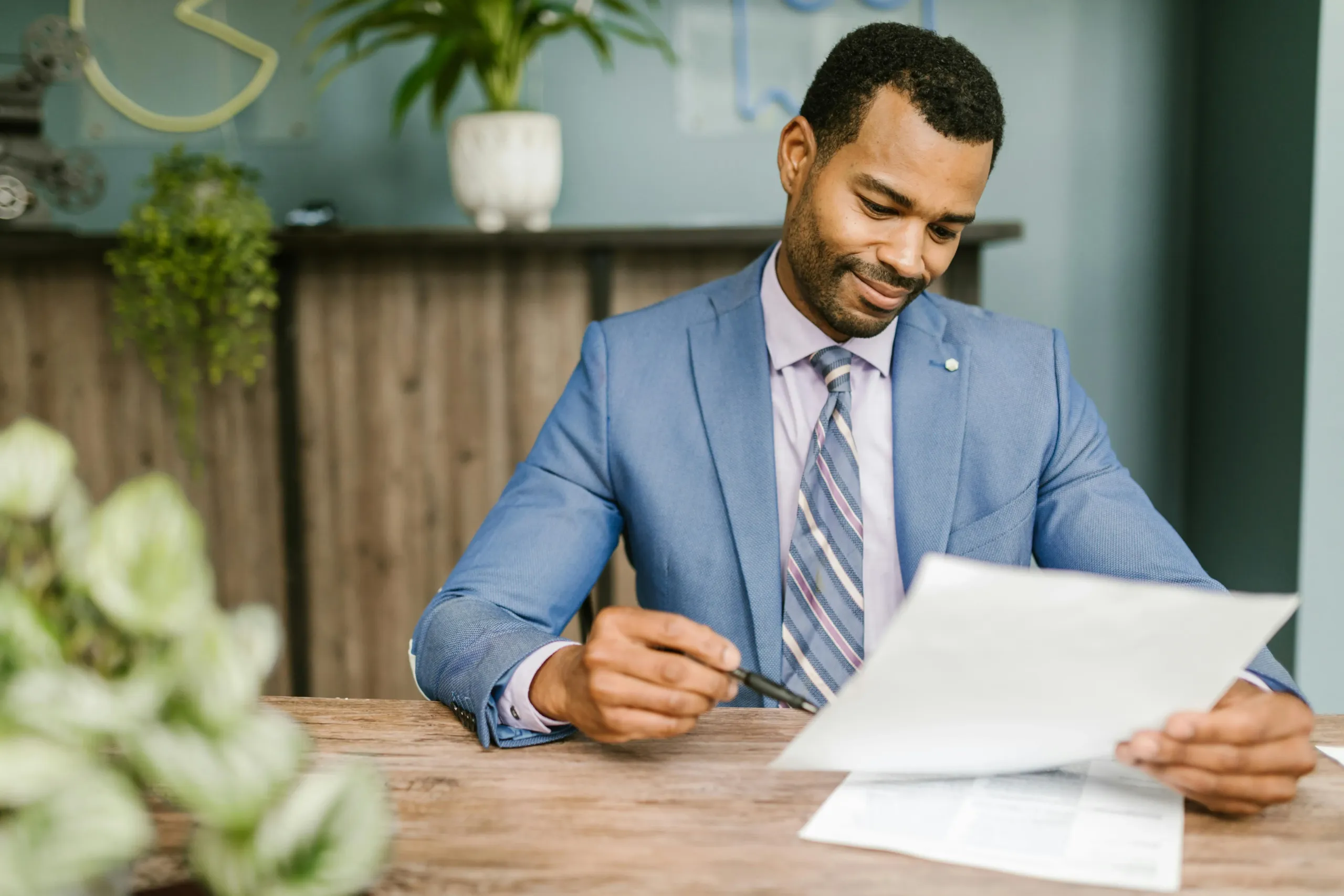 A professional energy broker in the UK wearing a blue suit jacket, holding a white paper and a ballpoint pen, symbolizing expertise and business negotiations.